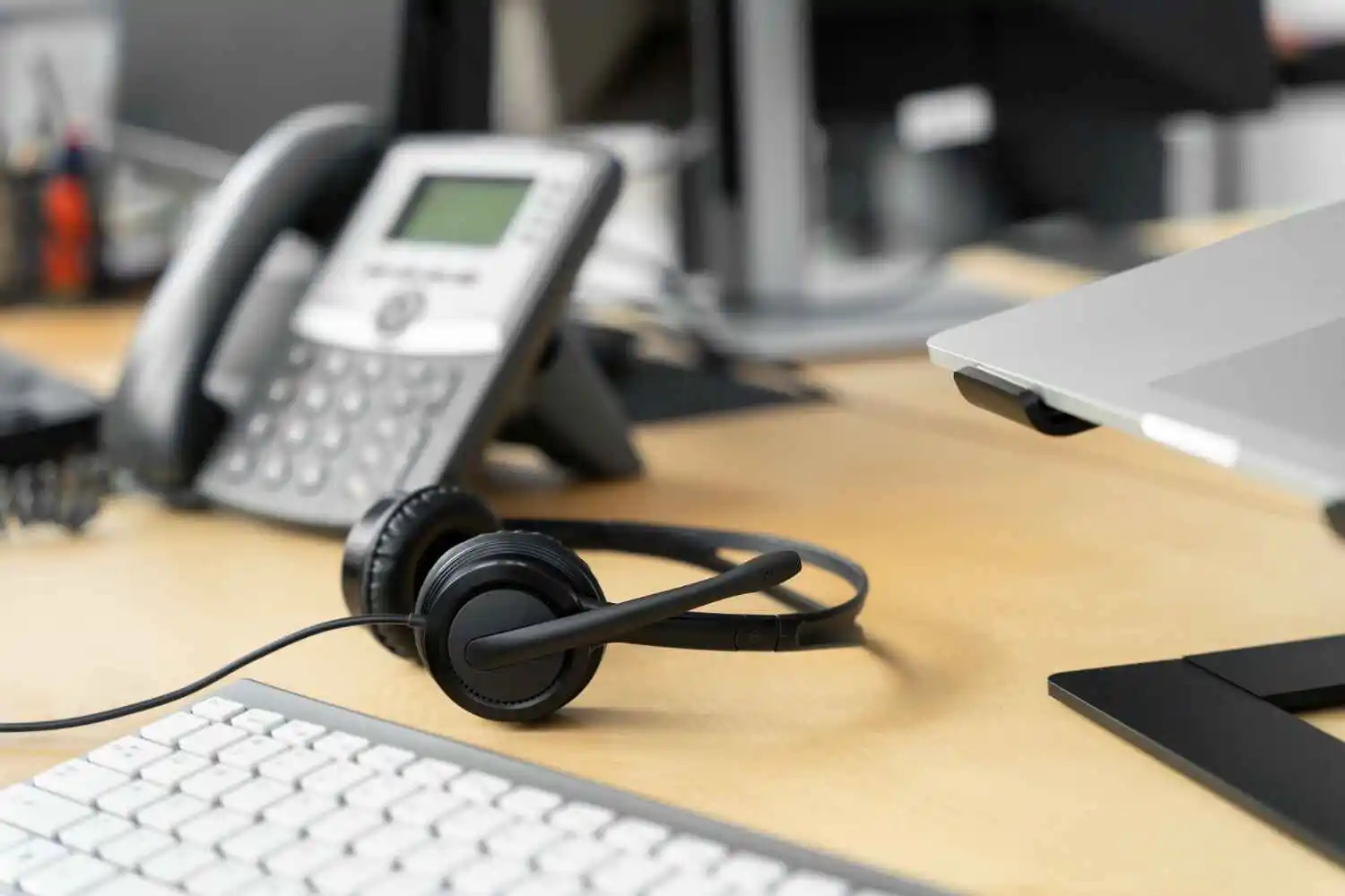 Fingerprint scanner placed on office desk alongside people in a business meeting, emphasizing secure access technology and professional communication solutions.