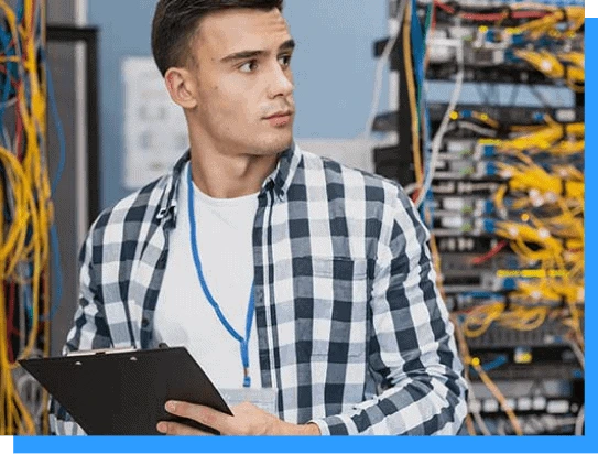 Young technician inspecting server racks with a clipboard in a data center for IT infrastructure management and network solutions.