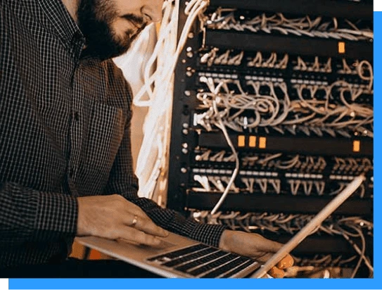 Server technician working on network infrastructure with cabling and rack-mounted equipment at Rivell data center.