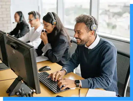 Customer service team working at computers with headsets in modern office environment.