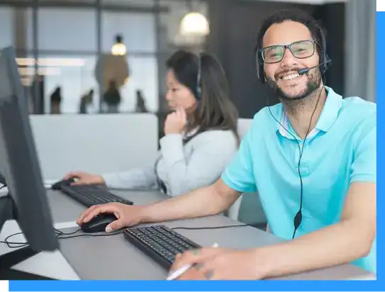 Support agent providing customer service at call center, smiling and wearing a headset in a modern office environment.