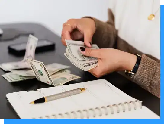 Stacks of US dollar bills being counted at a desk, representing financial management and cash handling.