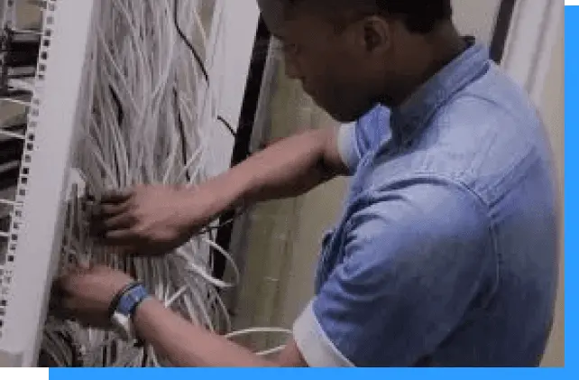 Wiring technician working on network cabling in data center or server room for IT infrastructure solutions.