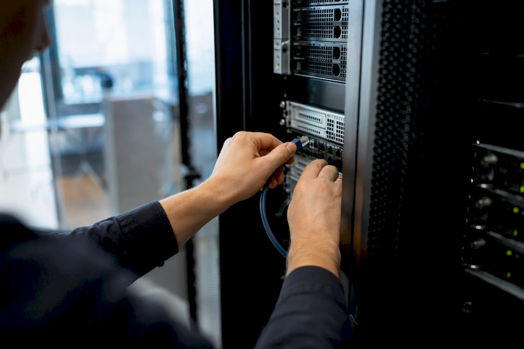 Technician hands connecting cable in server rack