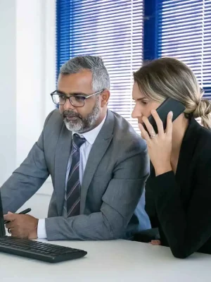 Voip office phone with headset, person making a call in modern workspace, professional communication device, business telecommunications, Rivell branding visible in background.